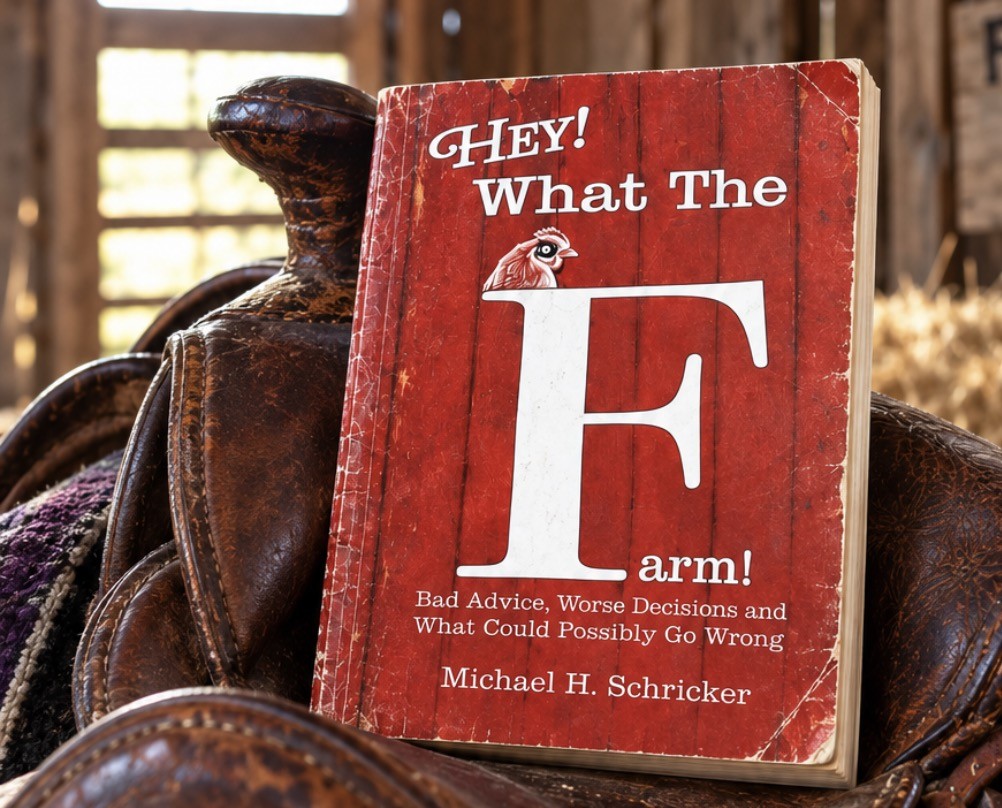 Hey! What The Farm! by Michael H. Schricker — the paperback propped on a saddle in the barn